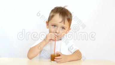 快乐的孩子通过吸管喝果汁喝鸡尾酒，坐在桌子旁，在白色背景上微笑